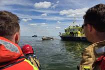 Een opstapper van KNRM station Urk en een manschap van brandweer Urk kijken toe hoe de restanten van de zeilboot worden geblust. 