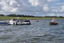 Het watermakende binnenvaartschip omringd door reddingboten. 
