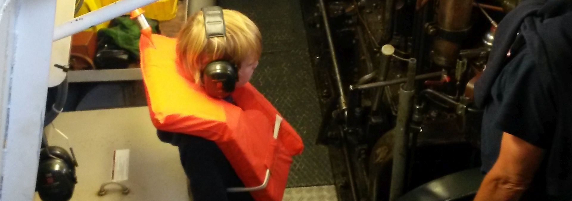 Een jonge gast mag in de motorruimte van de reddingboot kijken