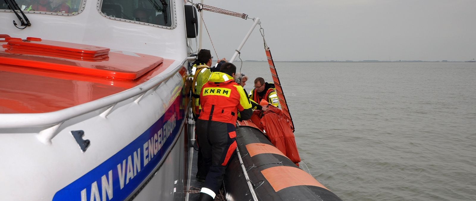De drenkeling wordt met de rescue cradle aan boord gehesen.