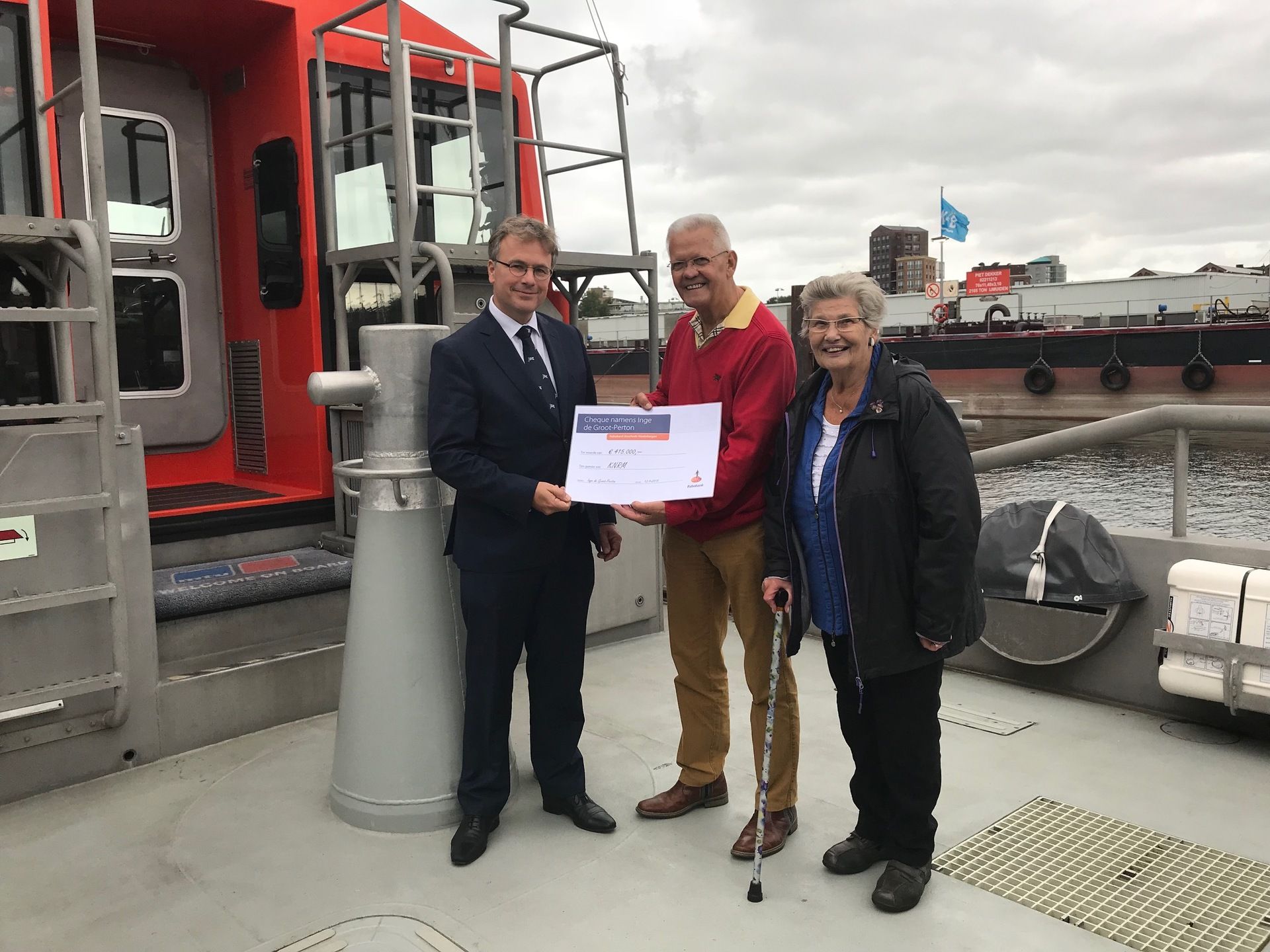 De heer en mevrouw Schenk bij de overhandiging van de cheque aan KNRM-directeur Dedan Schmidt (links
